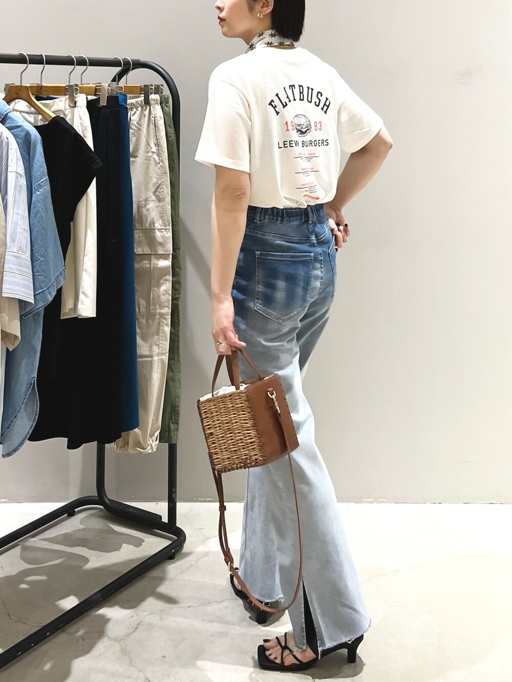 ブルー系のデニムパンツ、ブラック系のサンダル、ブラウン系のショルダーバッグを着用したレディースの夏コーディネートの3枚目の写真