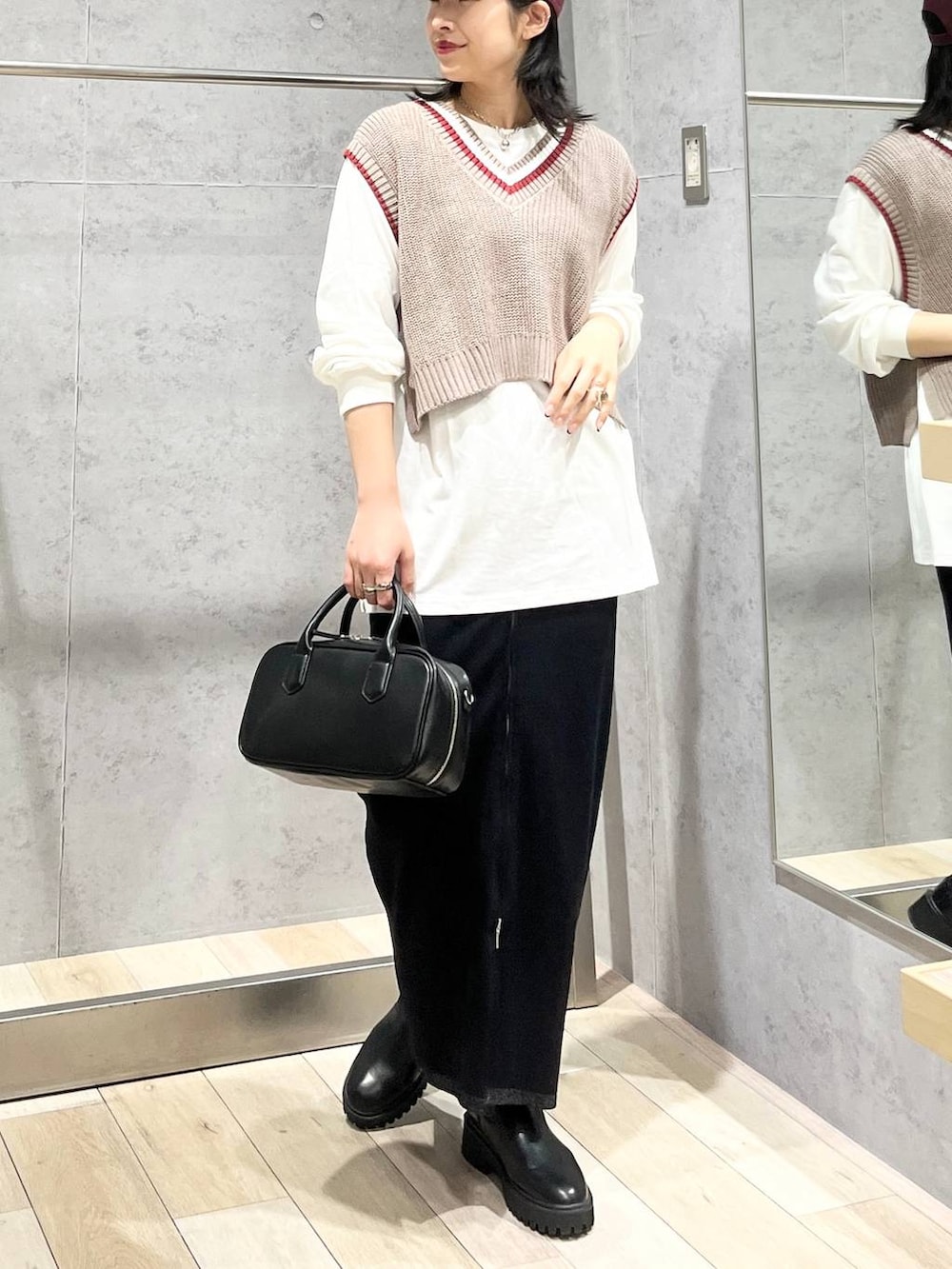 ブラック系のボストンバッグ、ブラック系のブーツ、ブラック系のスカートを着用したレディースの秋コーディネートの6枚目の写真