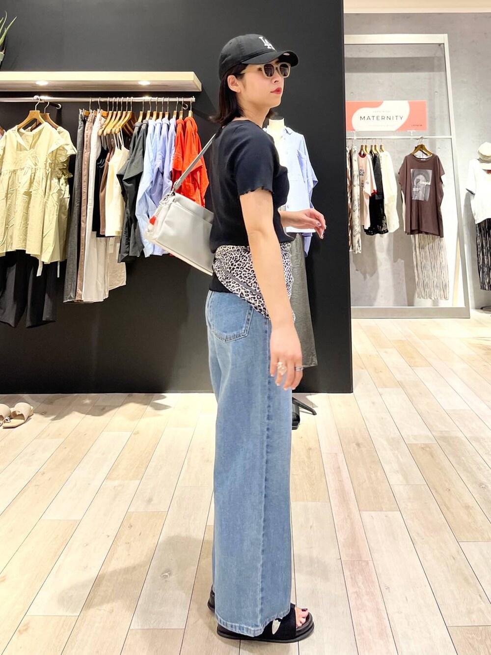 ブラック系のサンダル、ブルー系のデニムパンツ、グレー系のショルダーバッグを着用したレディースの夏コーディネートの3枚目の写真