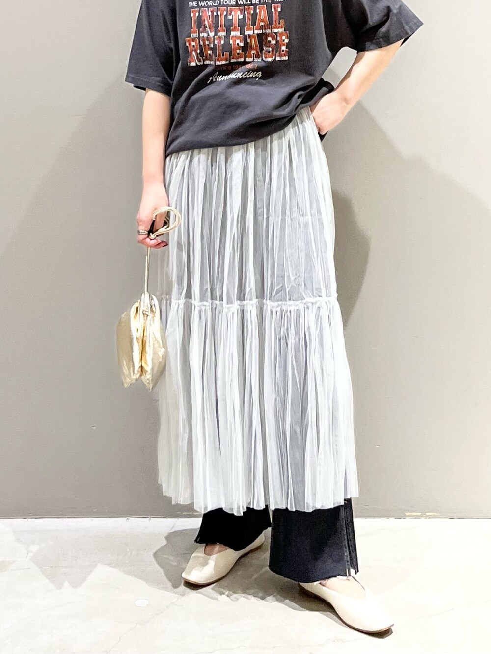 ブラック系のデニムパンツ、グレー系のスカート、ゴールド系のハンドバッグを着用したレディースの夏コーディネートの4枚目の写真