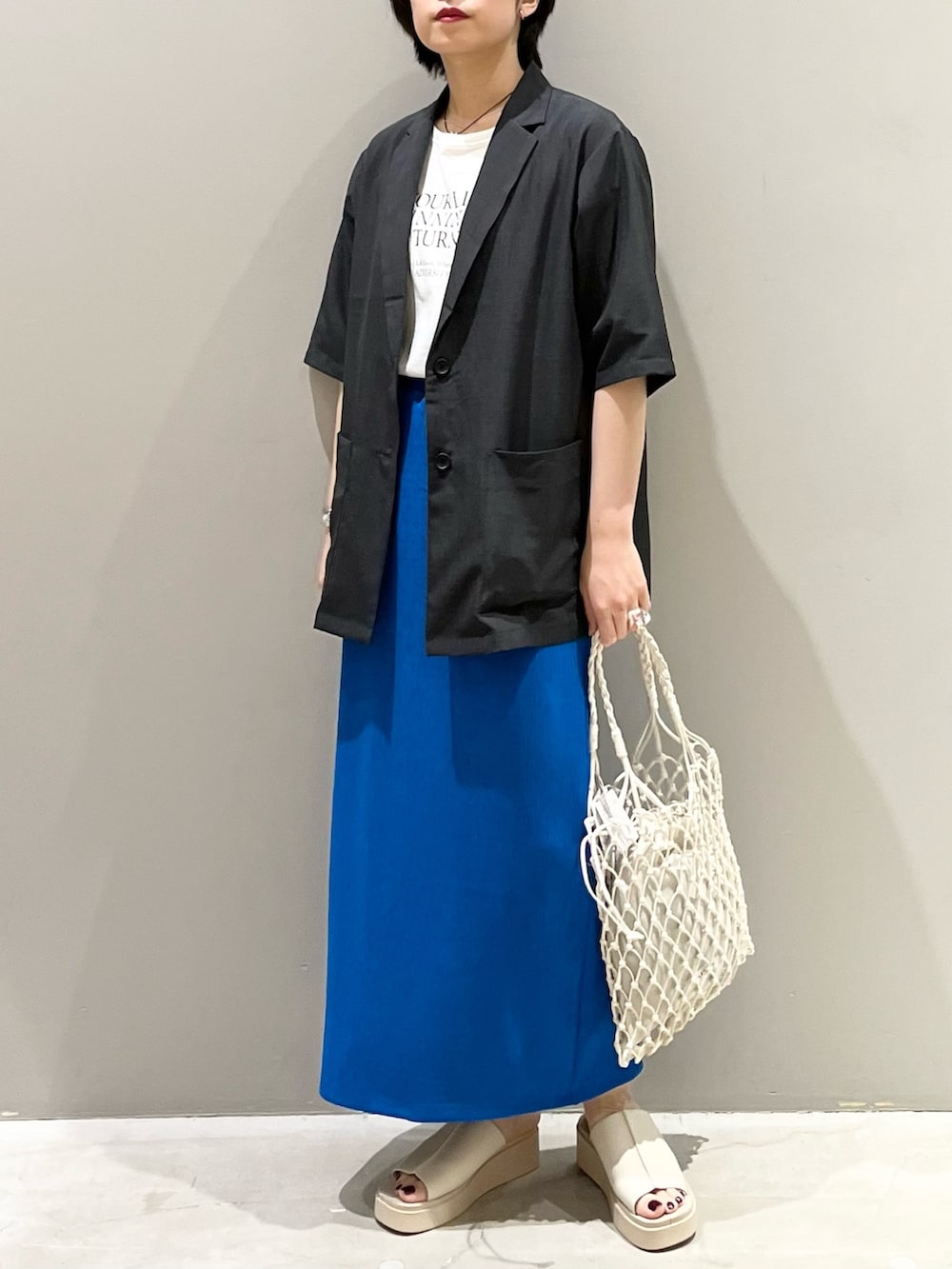 ブルー系のスカート、ホワイト系のトートバッグ、ベージュ系のサンダルを着用したレディースの夏コーディネートの5枚目の写真