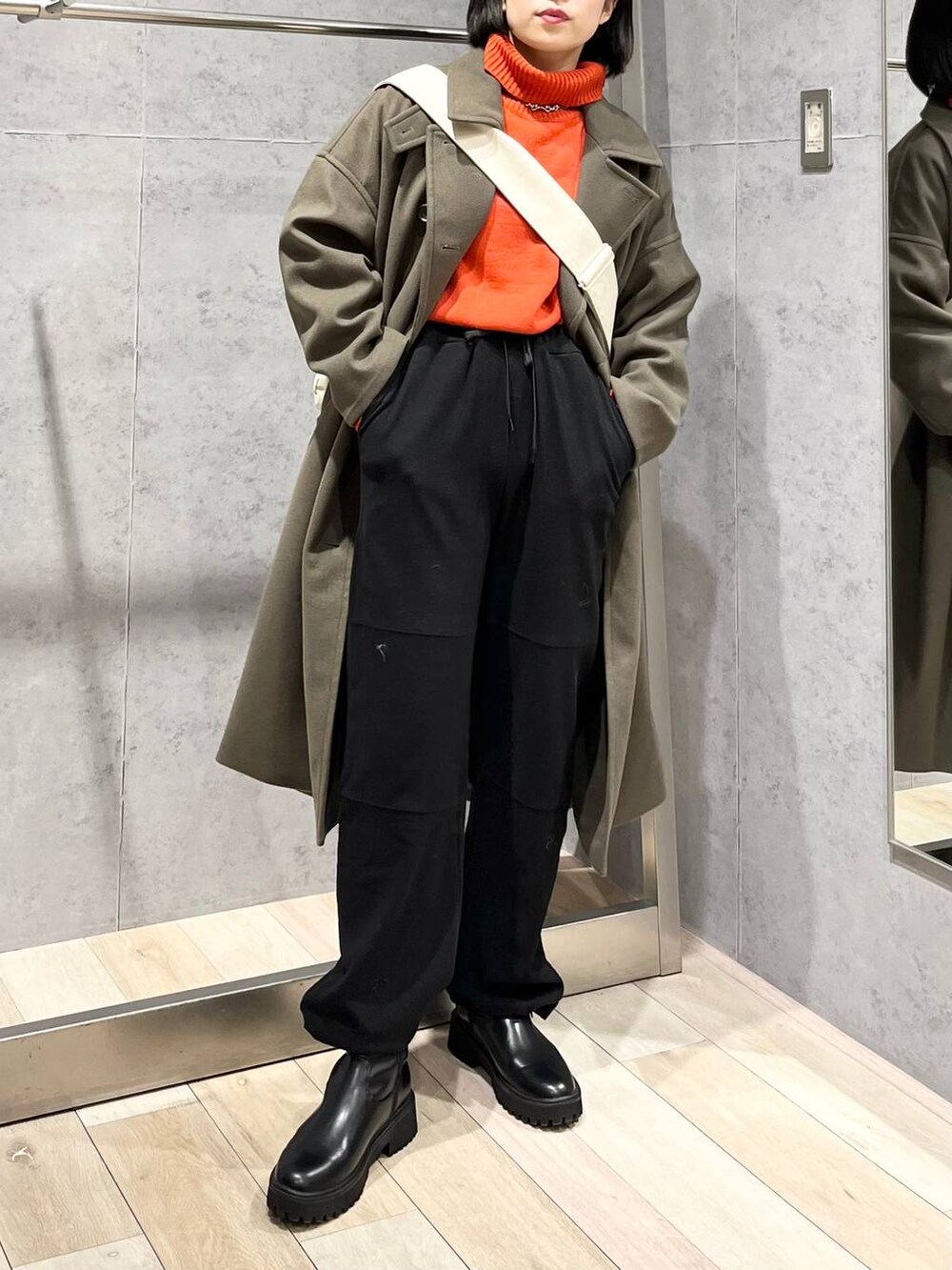 レッド系のニット/セーター、グリーン系のチェスターコート、ブラック系のブーツを着用したレディースの冬コーディネートの9枚目の写真