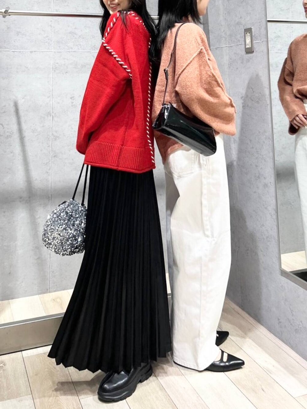 シルバー系のショルダーバッグ、ブラック系のブーツ、ホワイト系のデニムパンツを着用したレディースの冬コーディネートの3枚目の写真