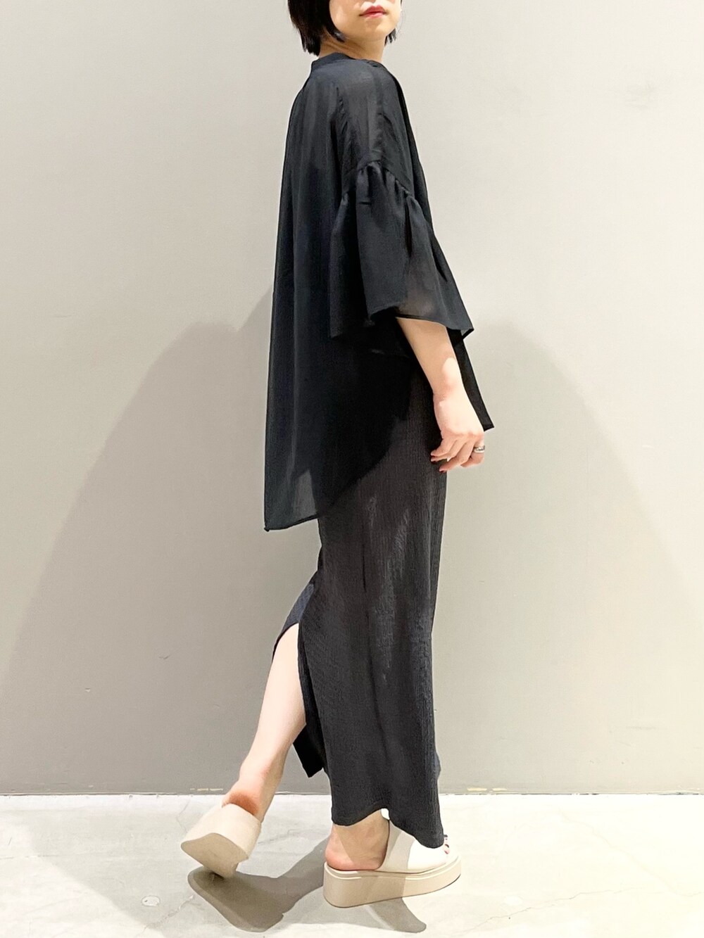 ベージュ系のサンダル、グレー系のスカート、グレー系のクラッチバッグを着用したレディースの夏コーディネートの5枚目の写真