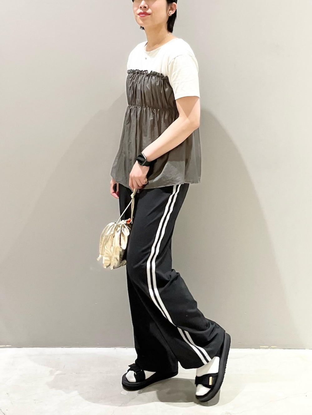 ブラック系のパンツ、ブラック系のサンダル、ゴールド系のハンドバッグを着用したレディースの秋コーディネートの6枚目の写真