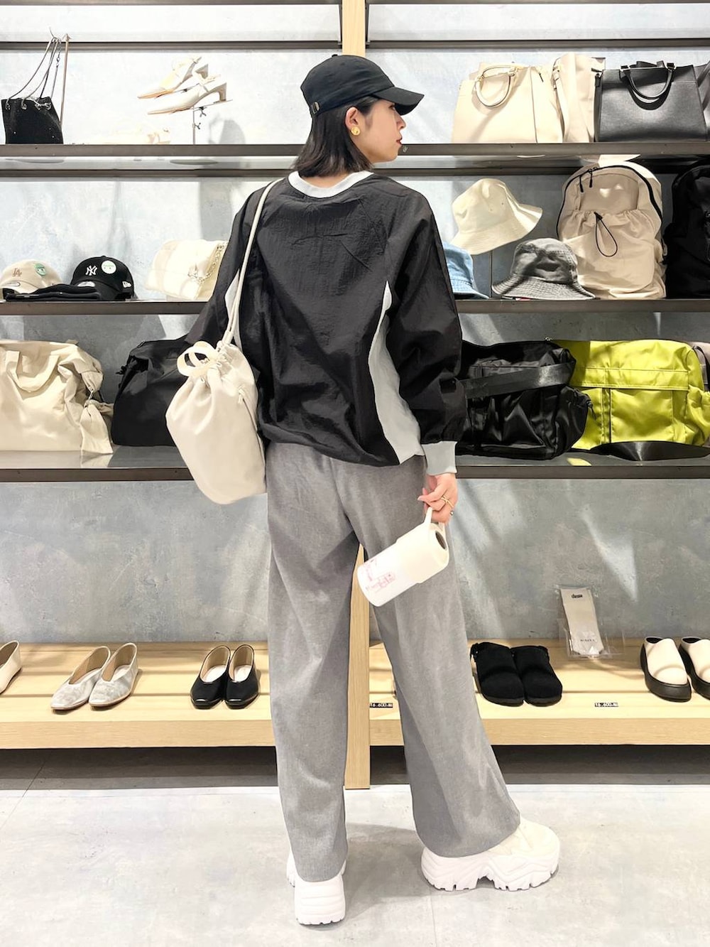 ホワイト系のスニーカー、ベージュ系のショルダーバッグ、グレー系のスラックスを着用したレディースの春コーディネートの5枚目の写真