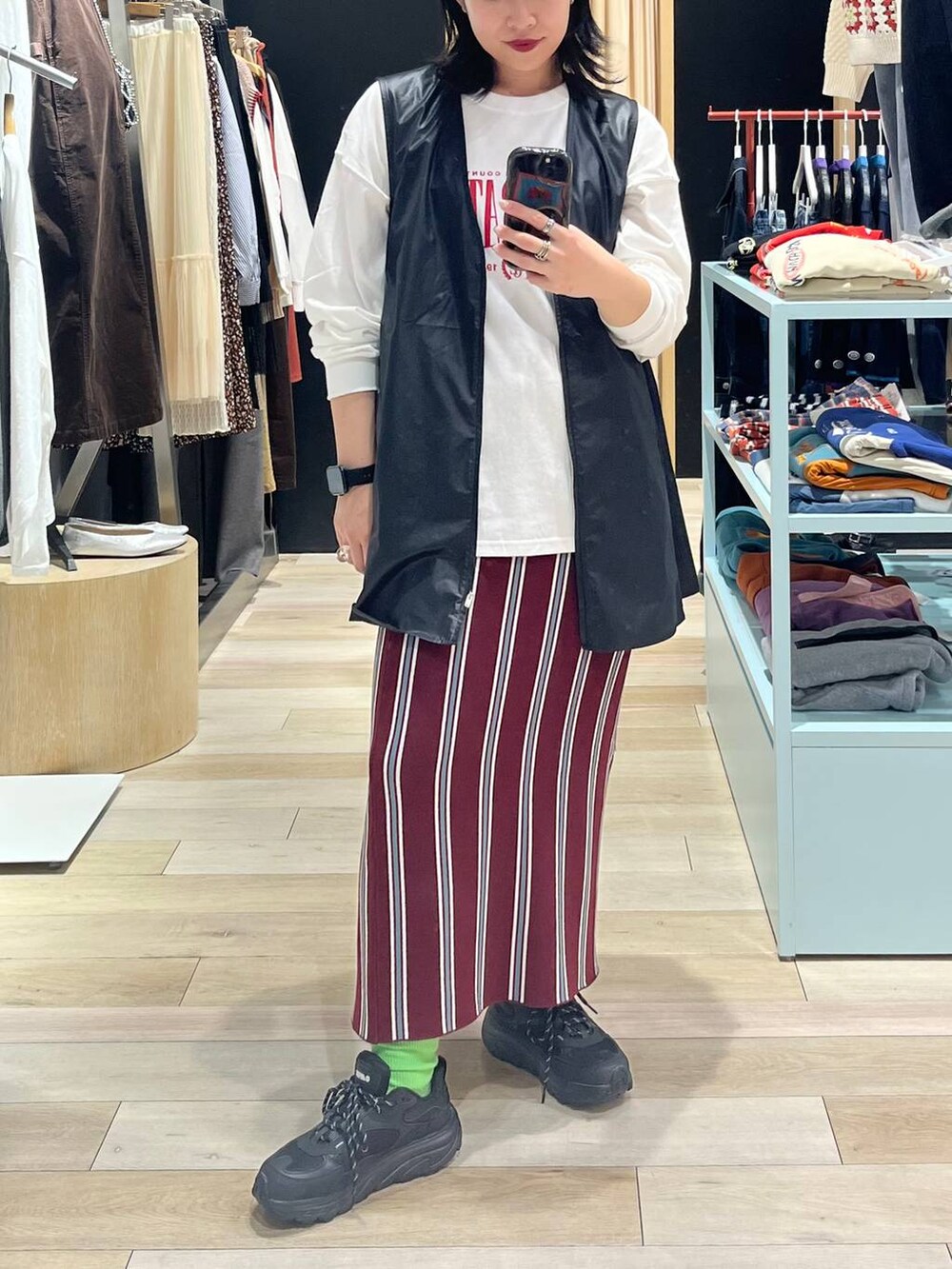 シルバー系のショルダーバッグ、レッド系のスカート、ブラック系のワンピースを着用したレディースの秋コーディネートの4枚目の写真