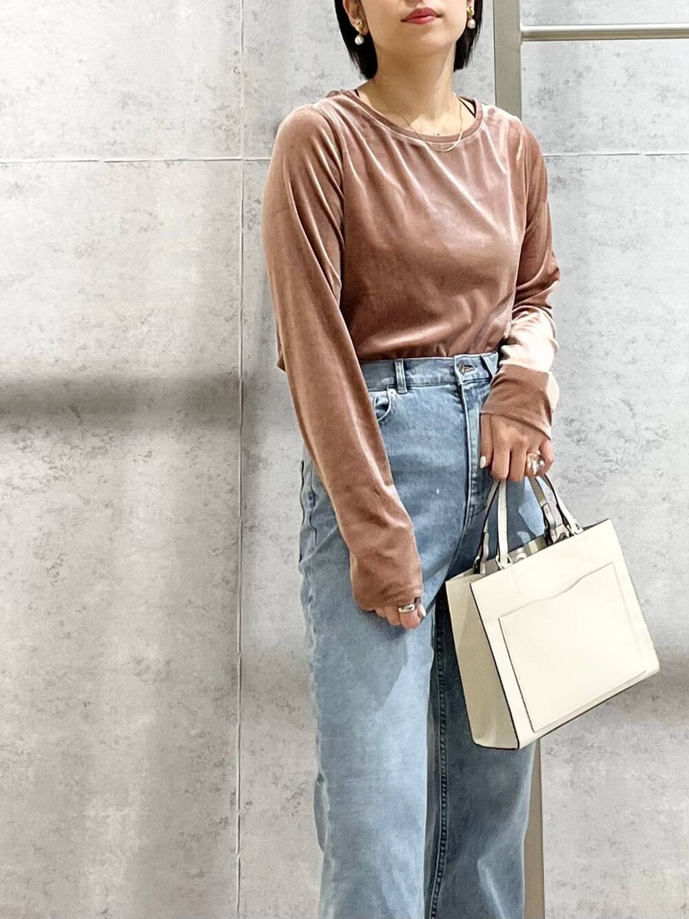 ブラック系のパンプス、ブルー系のデニムパンツ、ホワイト系のショルダーバッグを着用したレディースの秋コーディネートの4枚目の写真