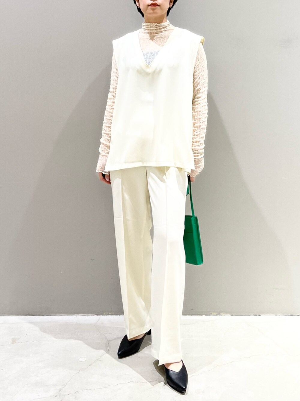 ホワイト系のベスト、グレー系のシューズ、グリーン系のバッグを着用したレディースの夏コーディネートの6枚目の写真