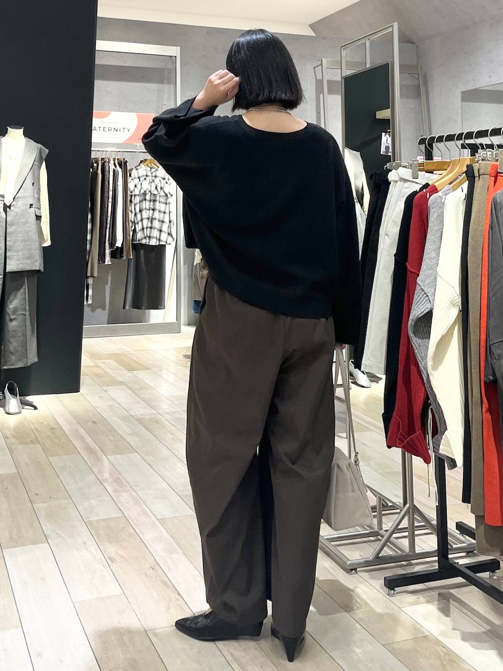 ブラック系のニット/セーター、ブラウン系のその他パンツ、ベージュ系のボストンバッグを着用したレディースの秋コーディネートの5枚目の写真