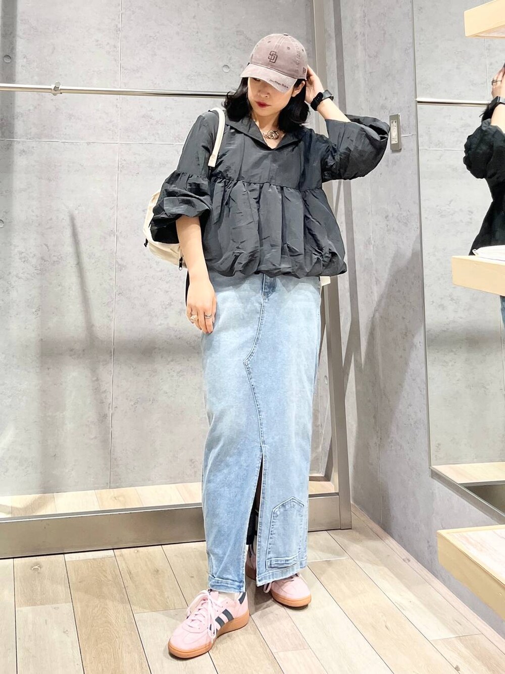 ホワイト系のショルダーバッグ、ブルー系のデニムスカート、ブラウン系のキャップを着用したレディースの冬コーディネートの3枚目の写真