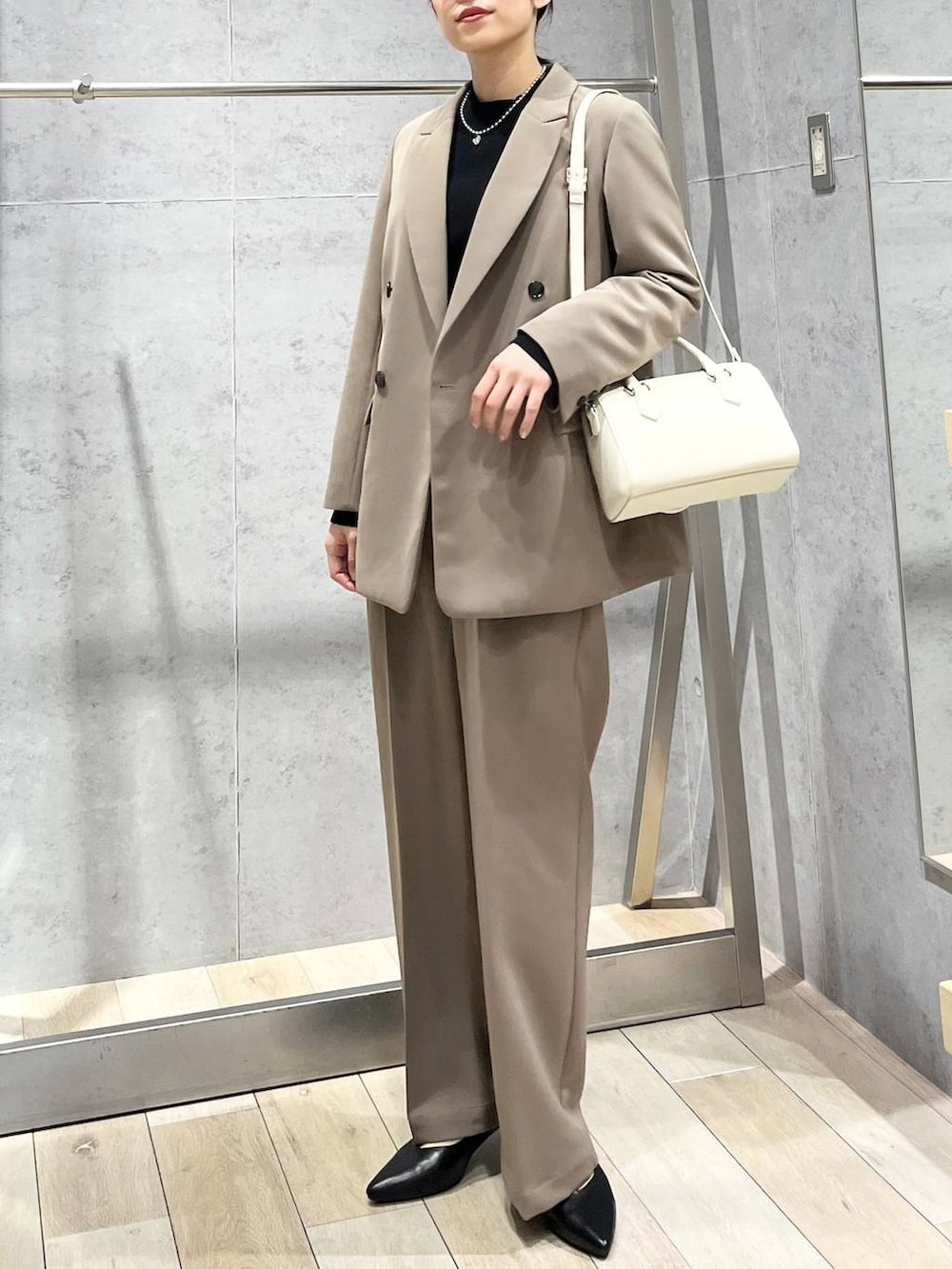 ブラック系のニット/セーター、ブラウン系のスーツパンツ、ブラック系のパンプスを着用したレディースの冬コーディネートの3枚目の写真