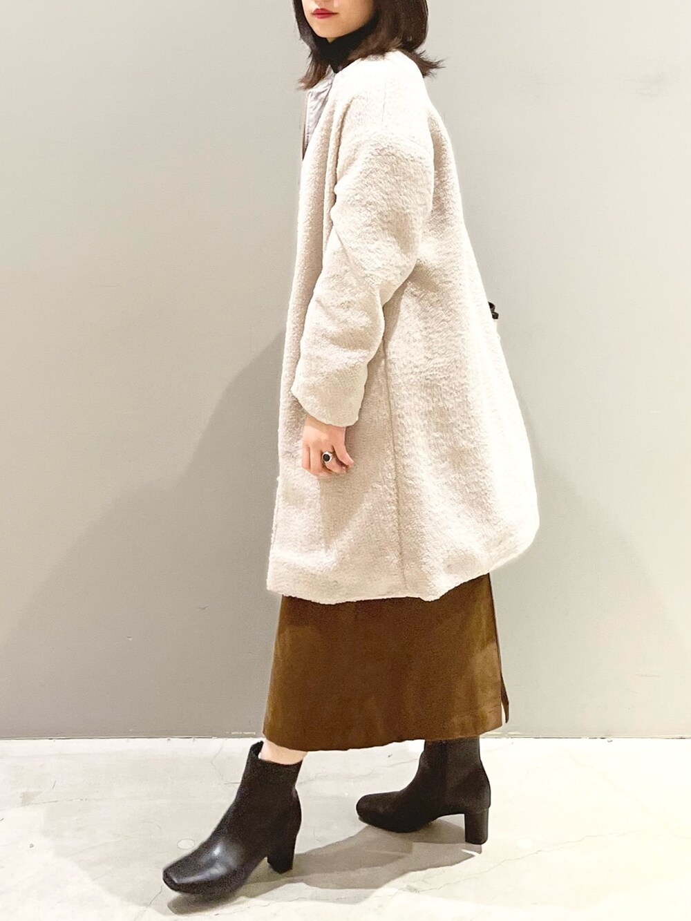 ブラック系のブーツ、ブラウン系のスカート、ホワイト系のショルダーバッグを着用したレディースの秋コーディネートの3枚目の写真