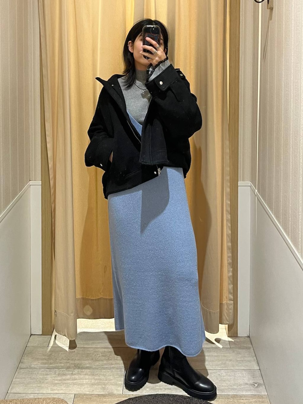 ブラック系のブルゾン、ブルー系のワンピース、ブラック系のブーツを着用したレディースの秋コーディネートの3枚目の写真