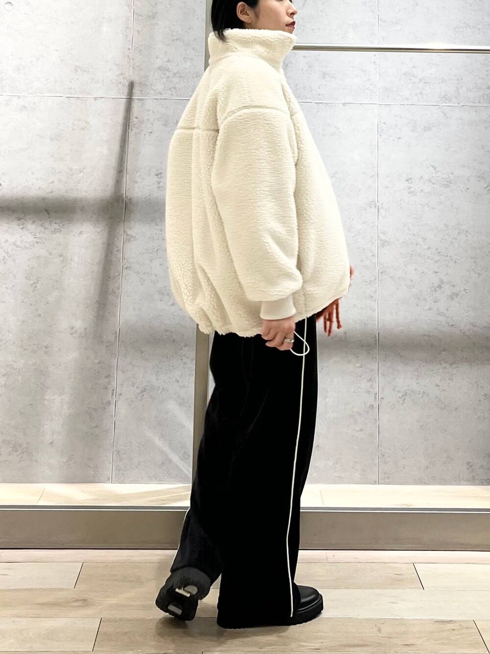 ブラック系のブーツ、ホワイト系のニット/セーター、ホワイト系のその他アウターを着用したレディースの冬コーディネートの3枚目の写真