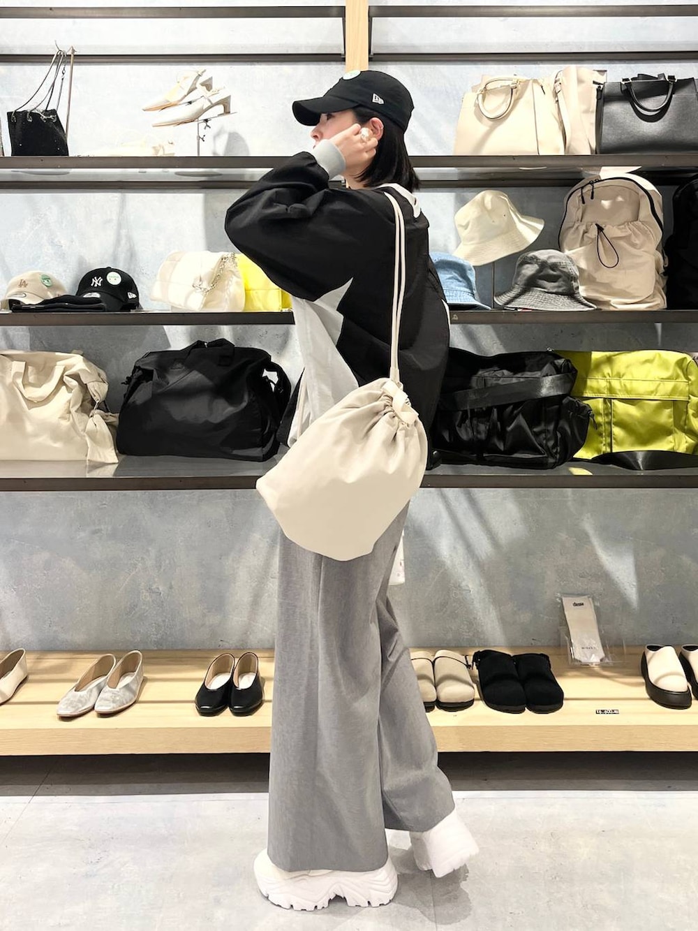 ホワイト系のスニーカー、ベージュ系のショルダーバッグ、グレー系のスラックスを着用したレディースの春コーディネートの4枚目の写真