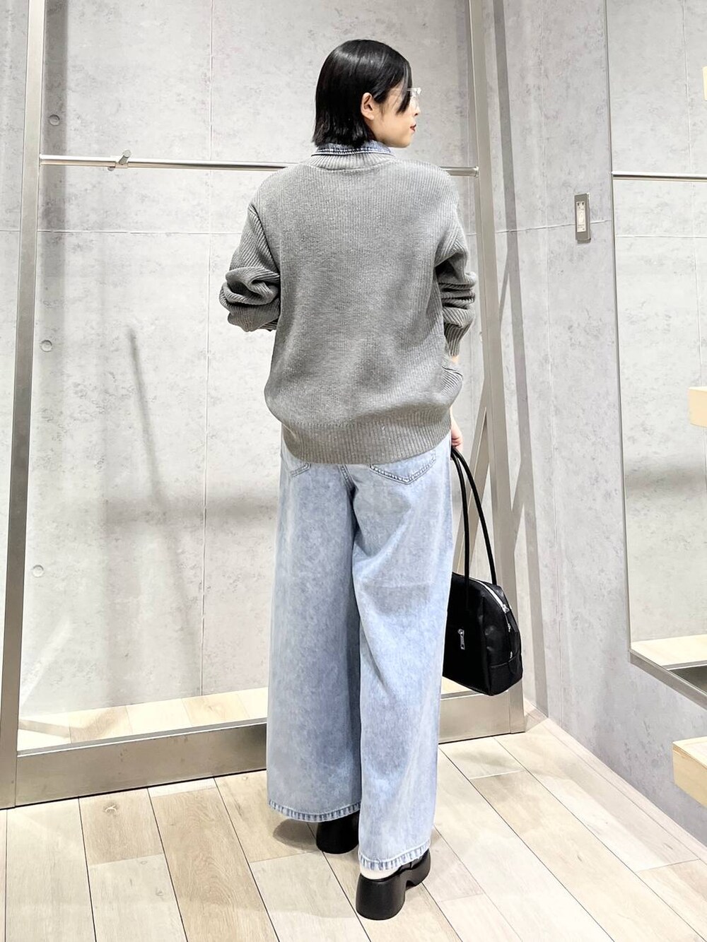 ブラック系のサンダル、ブルー系のデニムパンツ、ブラック系のボストンバッグを着用したレディースの冬コーディネートの4枚目の写真