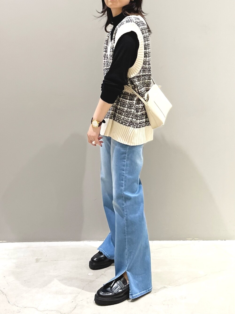 ブルー系のデニムパンツ、ブラック系のローファー、ホワイト系のショルダーバッグを着用したレディースの秋コーディネートの3枚目の写真