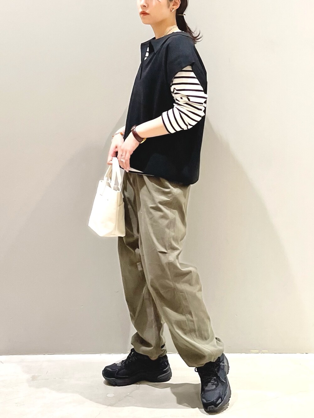 ブラック系のスニーカー、グリーン系のカーゴパンツ、ホワイト系のトートバッグを着用したレディースの秋コーディネートの2枚目の写真