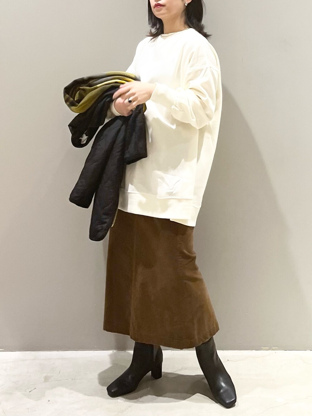 ブラウン系のスカート、ブラック系のブーツ、ブラック系のジャケット/アウターを着用したレディースの秋コーディネートの2枚目の写真