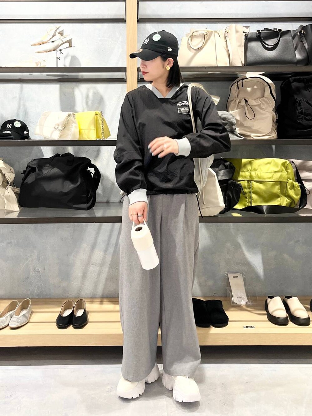 ホワイト系のスニーカー、ベージュ系のショルダーバッグ、グレー系のスラックスを着用したレディースの春コーディネートの6枚目の写真