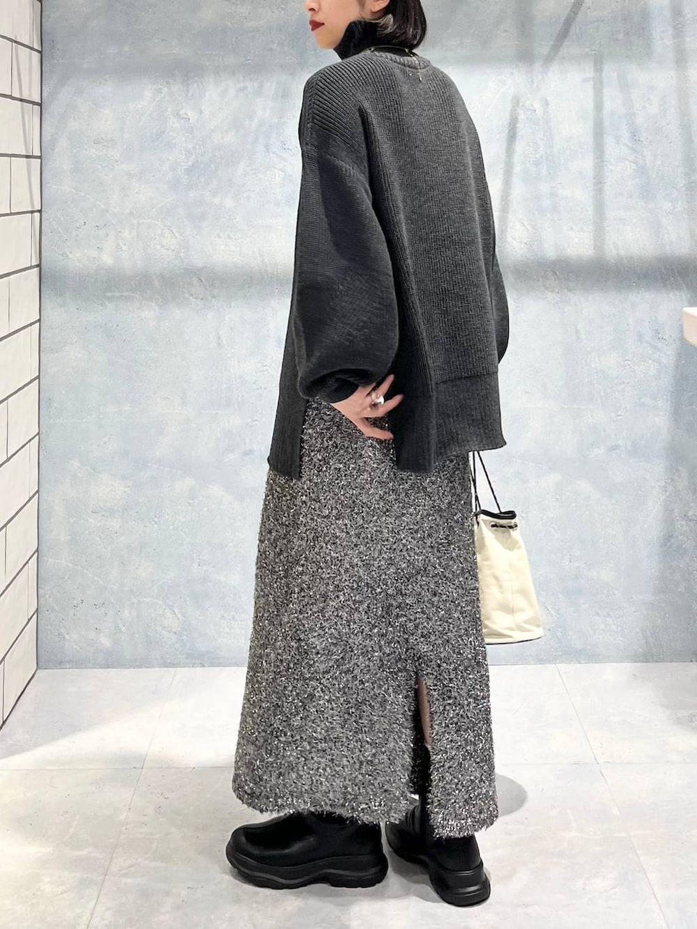 グレー系のTシャツ/カットソー、ブラック系のブーツ、ブラック系のスカートを着用したレディースの冬コーディネートの5枚目の写真