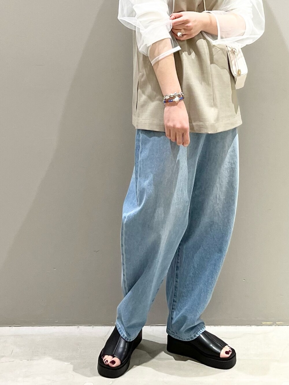 ブルー系のデニムパンツ、ホワイト系のサンダル、ブラック系のバッグを着用したレディースの春コーディネートの6枚目の写真