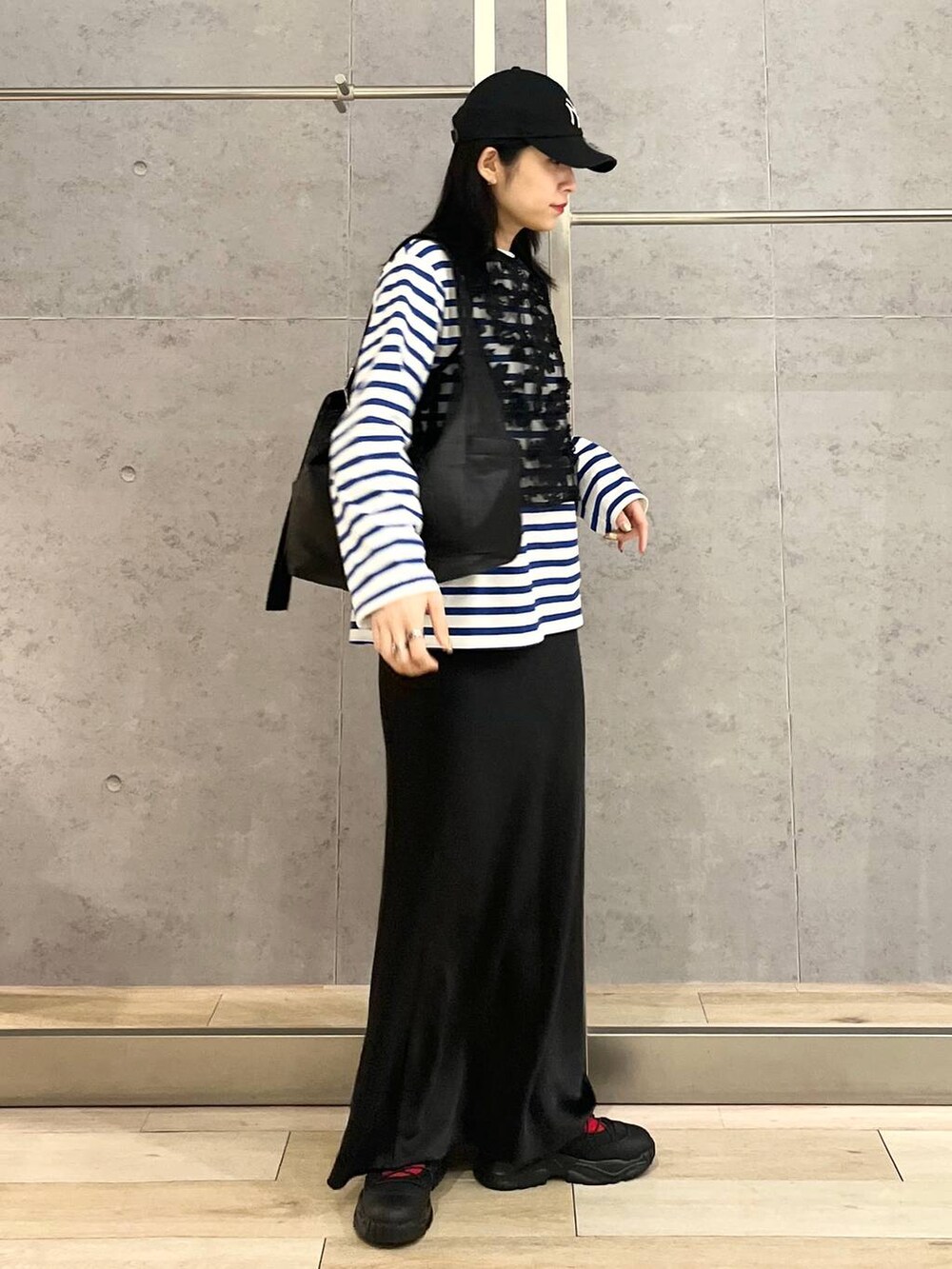 ブラック系のスカート、ブルー系のTシャツ/カットソー、ブラック系のスニーカーを着用したレディースの冬コーディネートの7枚目の写真