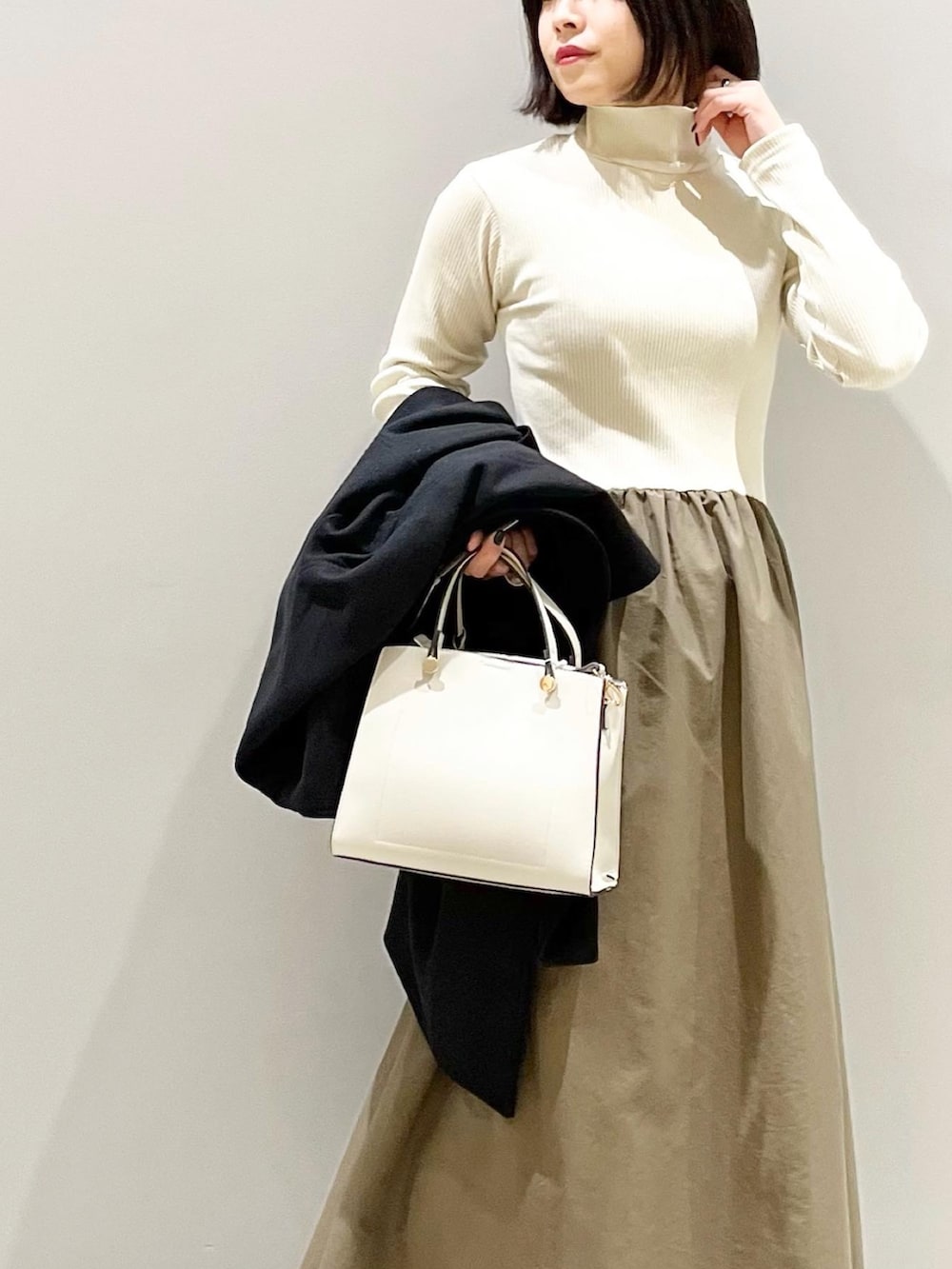 ブラック系のジャケット/アウター、グリーン系のワンピース、ホワイト系のショルダーバッグを着用したレディースの冬コーディネートの4枚目の写真