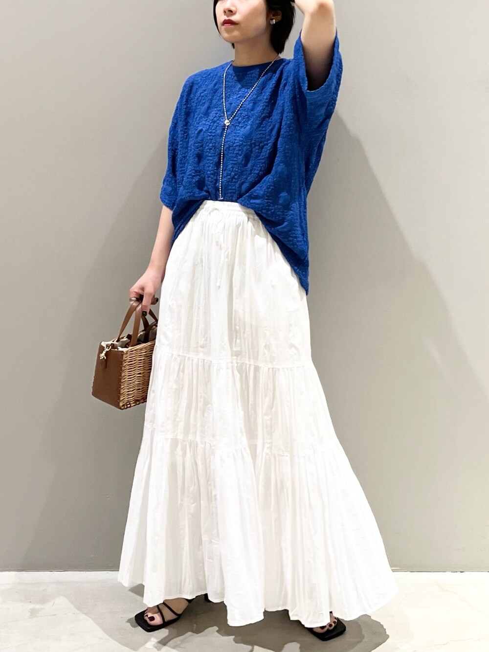 ブラック系のサンダル、ブラウン系のショルダーバッグ、ホワイト系のスカートを着用したレディースの夏コーディネートの8枚目の写真