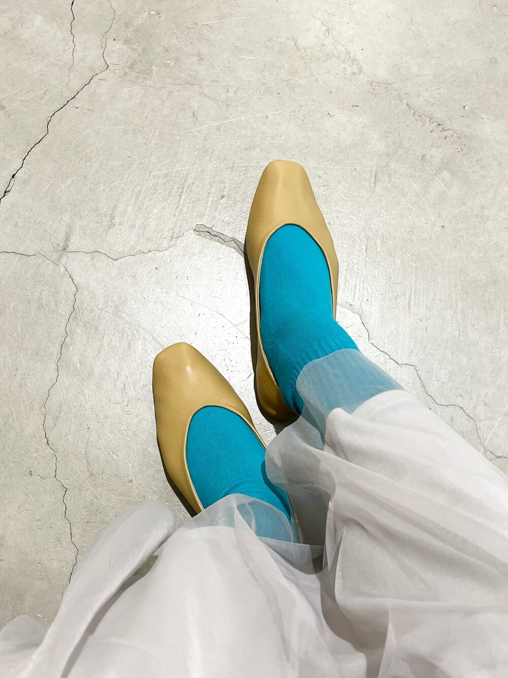 グレー系のスカート、イエロー系のパンプス、ブラック系のパンプスを着用したレディースの冬コーディネートの2枚目の写真