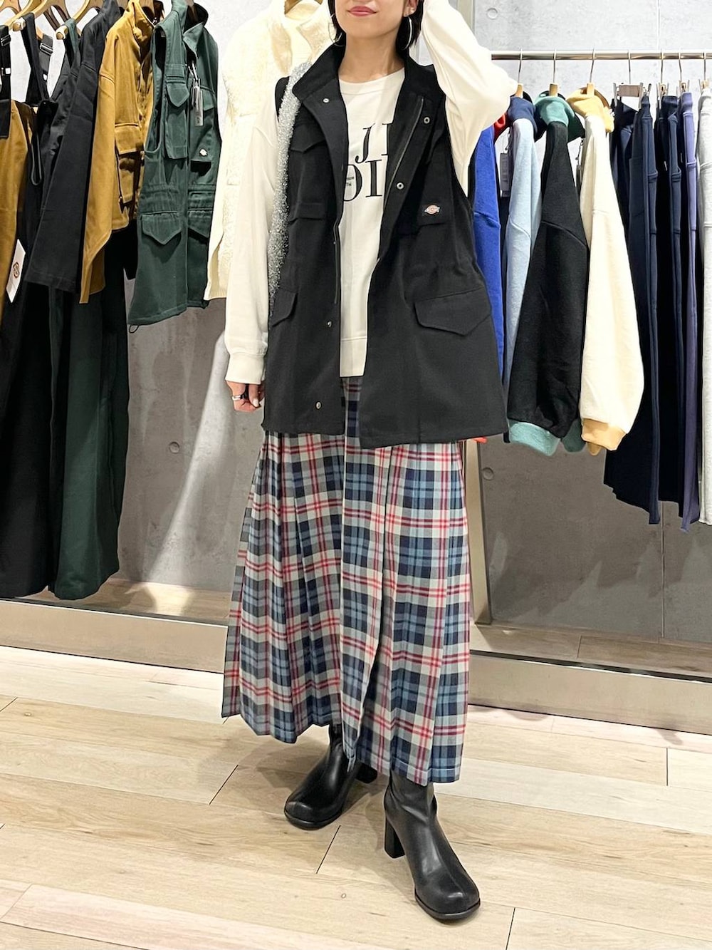 ブラック系のベスト、ホワイト系のスウェット、ブラック系のブーツを着用したレディースの秋コーディネートの5枚目の写真