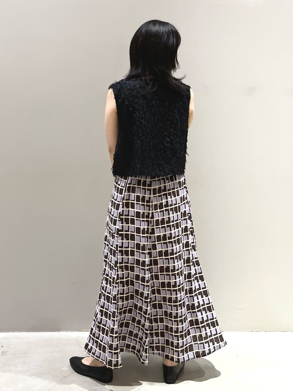 ホワイト系のバッグ、ブラック系のパンプス、ブラウン系のスカートを着用したレディースの秋コーディネートの2枚目の写真