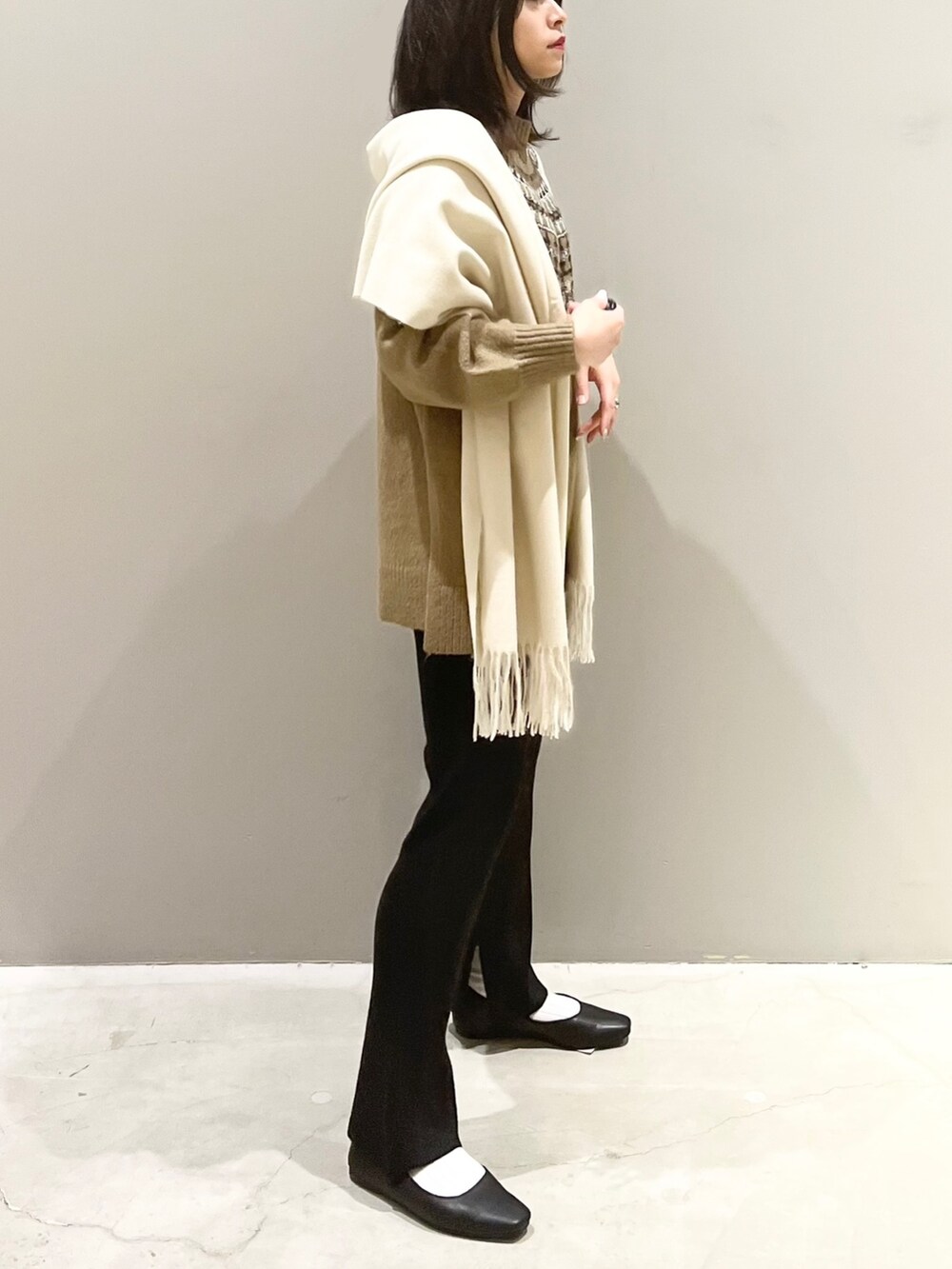 ブラック系のその他パンツ、ブラック系のパンプス、ホワイト系のストール/ショールを着用したレディースの秋コーディネートの3枚目の写真