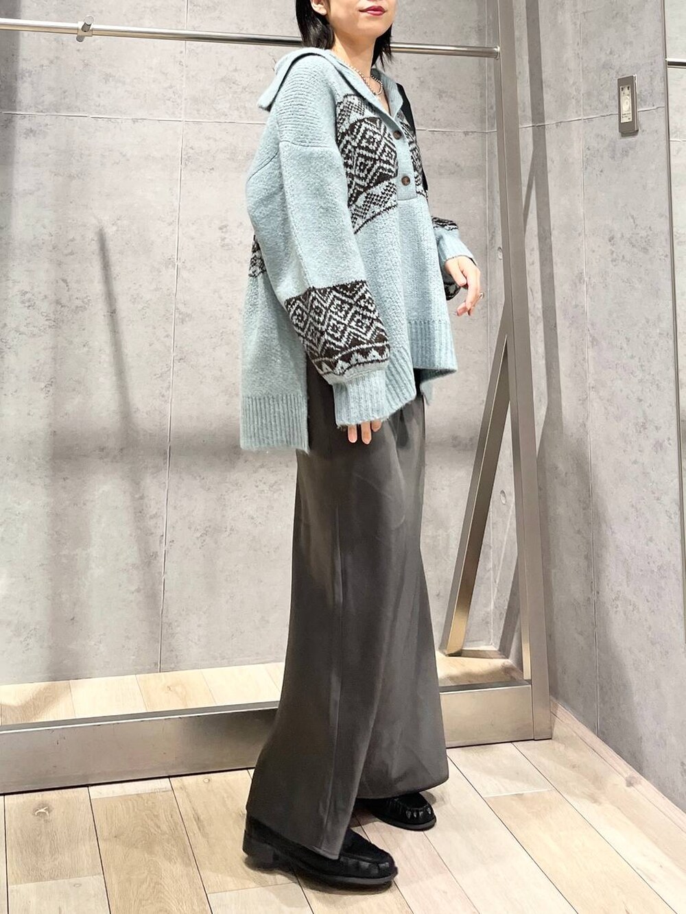 ブラック系のショルダーバッグ、グレー系のスカート、ブラック系のローファーを着用したレディースの秋コーディネートの3枚目の写真