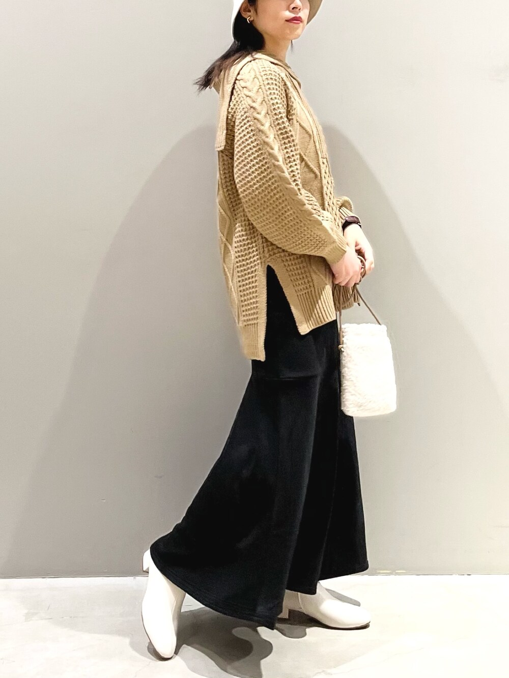 イエロー系のニット/セーター、ブラック系のスカート、ホワイト系のブーツを着用したレディースの秋コーディネートの3枚目の写真
