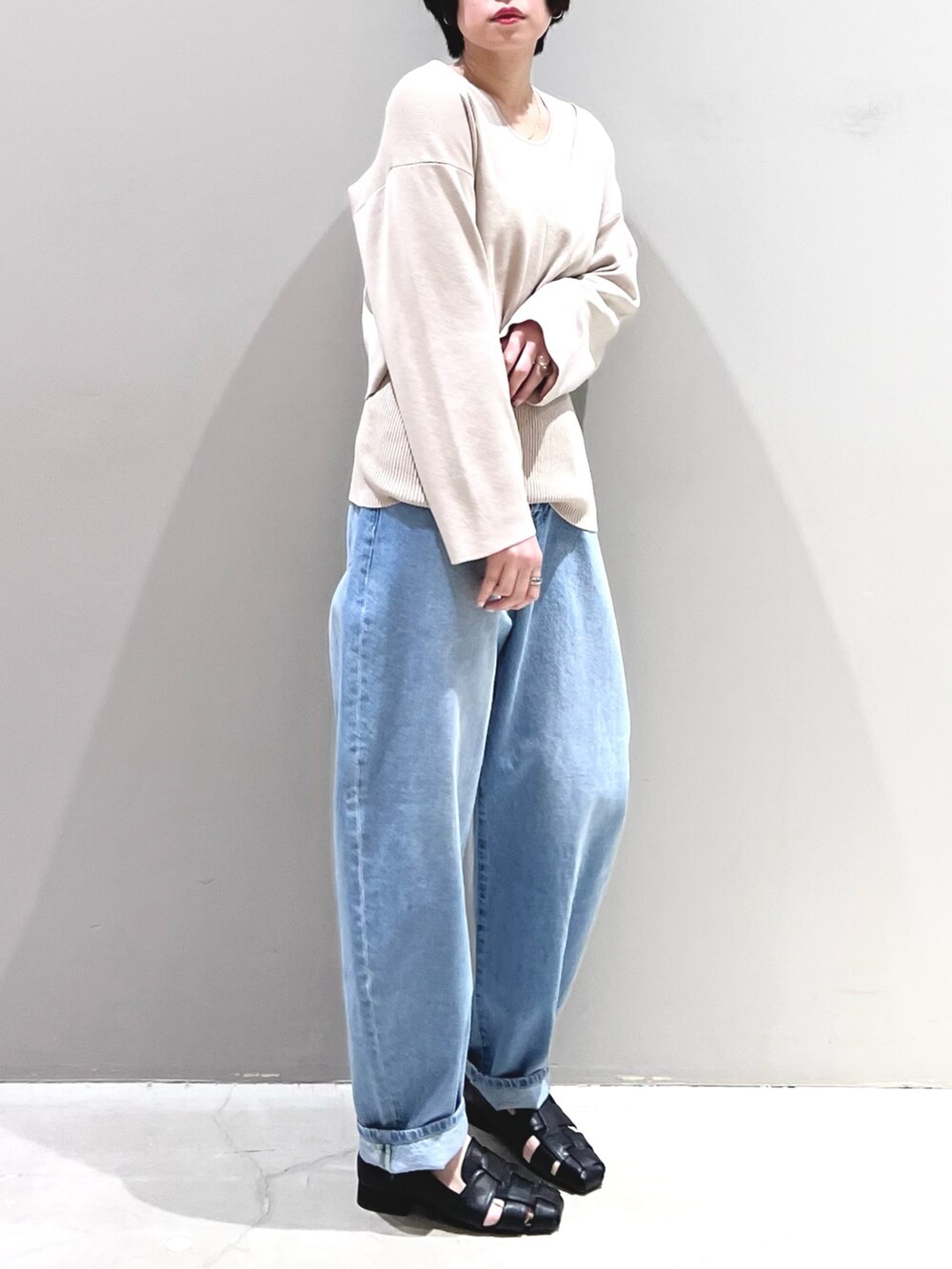 ブルー系のデニムパンツ、ブラック系のシューズ、ベージュ系のニット/セーターを着用したレディースの春コーディネートの4枚目の写真