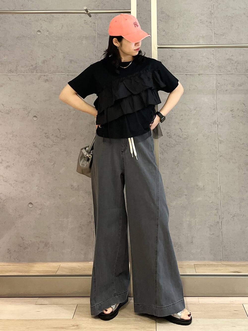 シルバー系のサンダル、ブラック系のデニムパンツ、ホワイト系のショルダーバッグを着用したレディースの春コーディネートの2枚目の写真