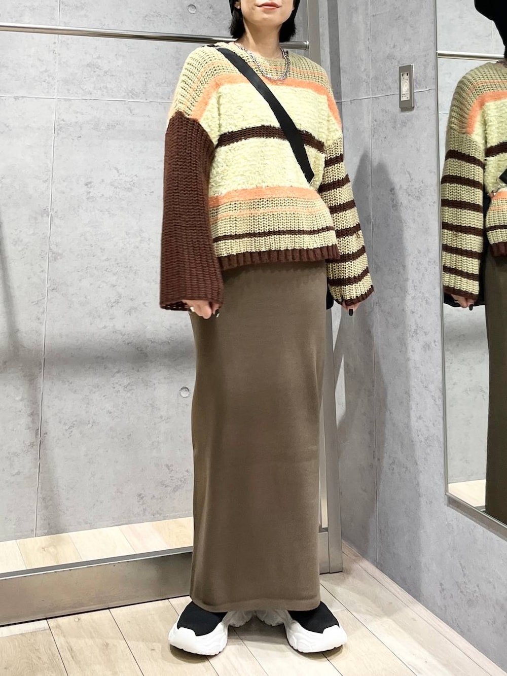 ブラウン系のスカート、ブラウン系のニット/セーター、ブラック系のブーツを着用したレディースの秋コーディネートの3枚目の写真