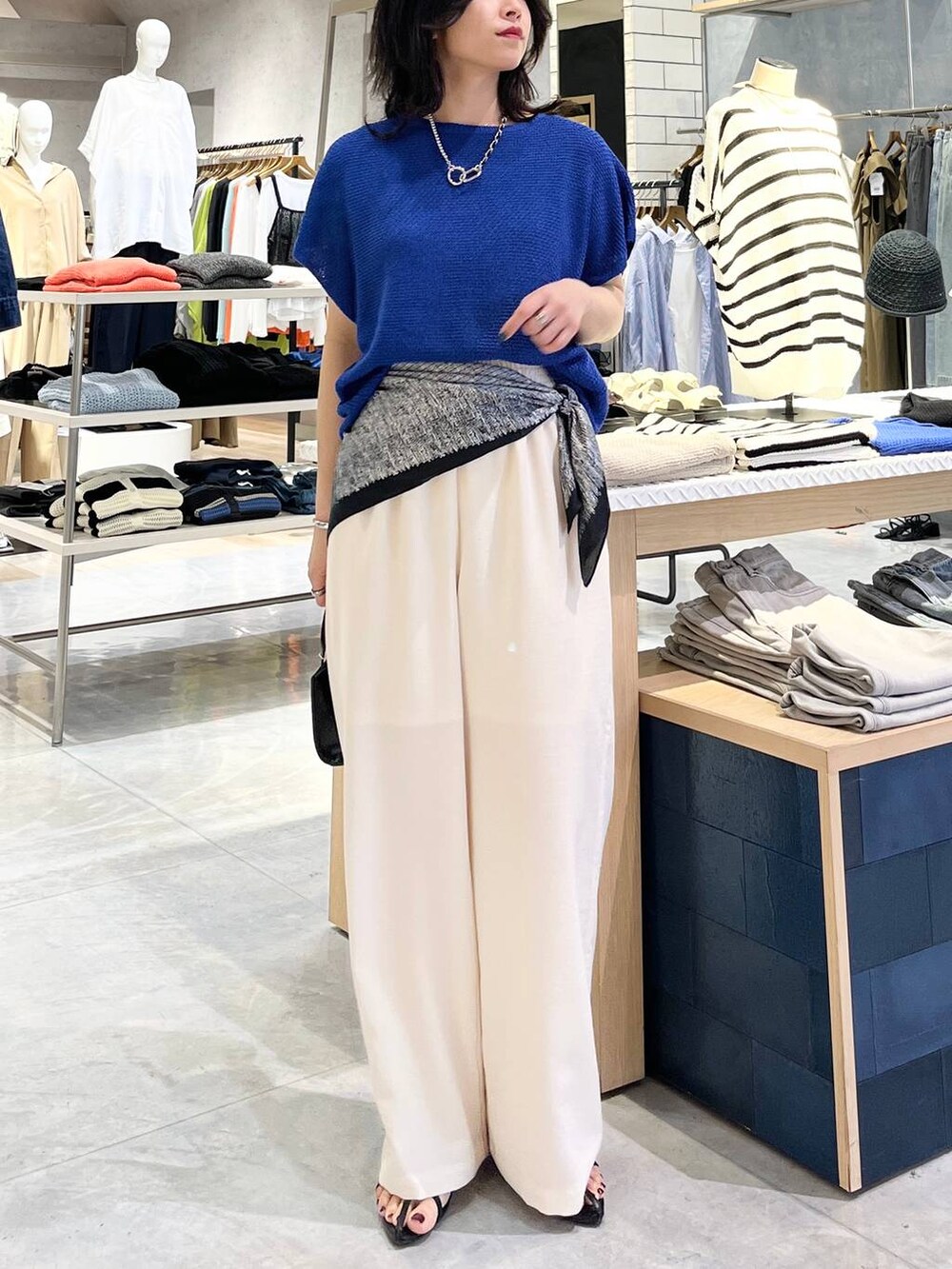 ブルー系のニット/セーター、ホワイト系のその他パンツ、ブラック系のサンダルを着用したレディースの春コーディネートの2枚目の写真