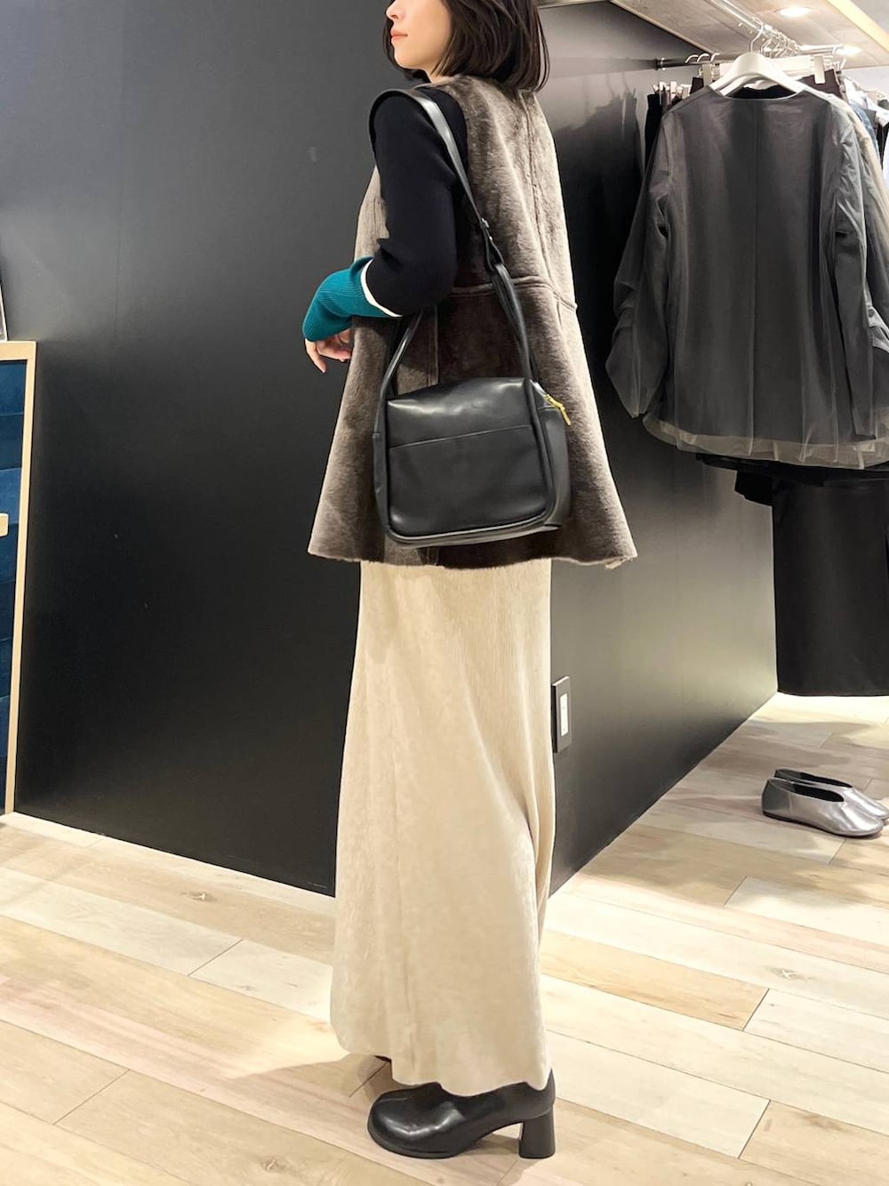 ブラック系のニット/セーター、ブラック系のブーツ、ブラック系のショルダーバッグを着用したレディースの秋コーディネートの5枚目の写真