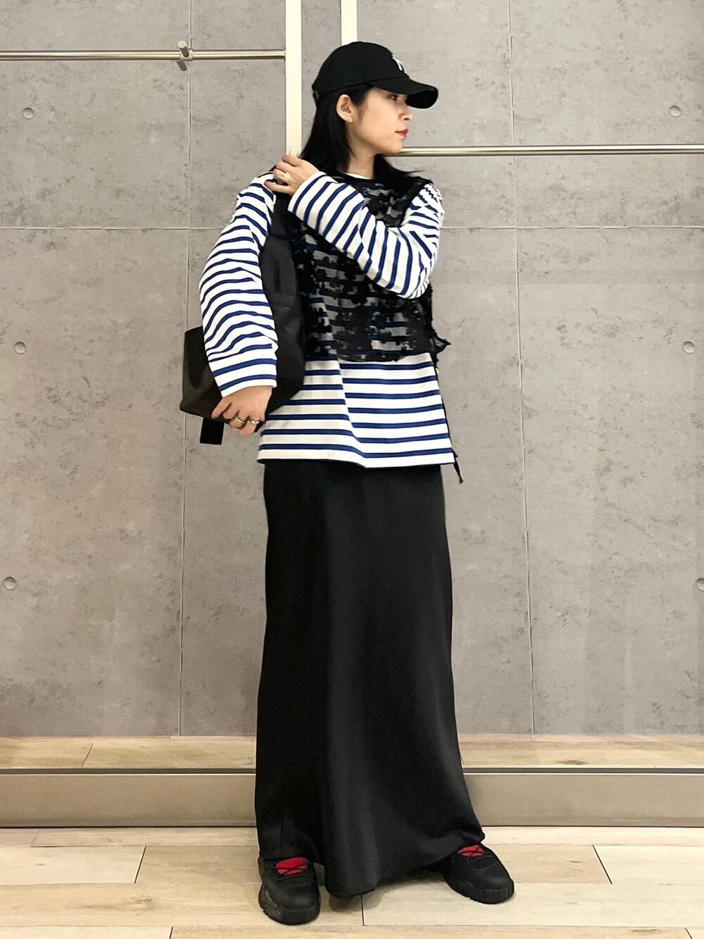 ブラック系のスカート、ブルー系のTシャツ/カットソー、ブラック系のスニーカーを着用したレディースの冬コーディネートの2枚目の写真