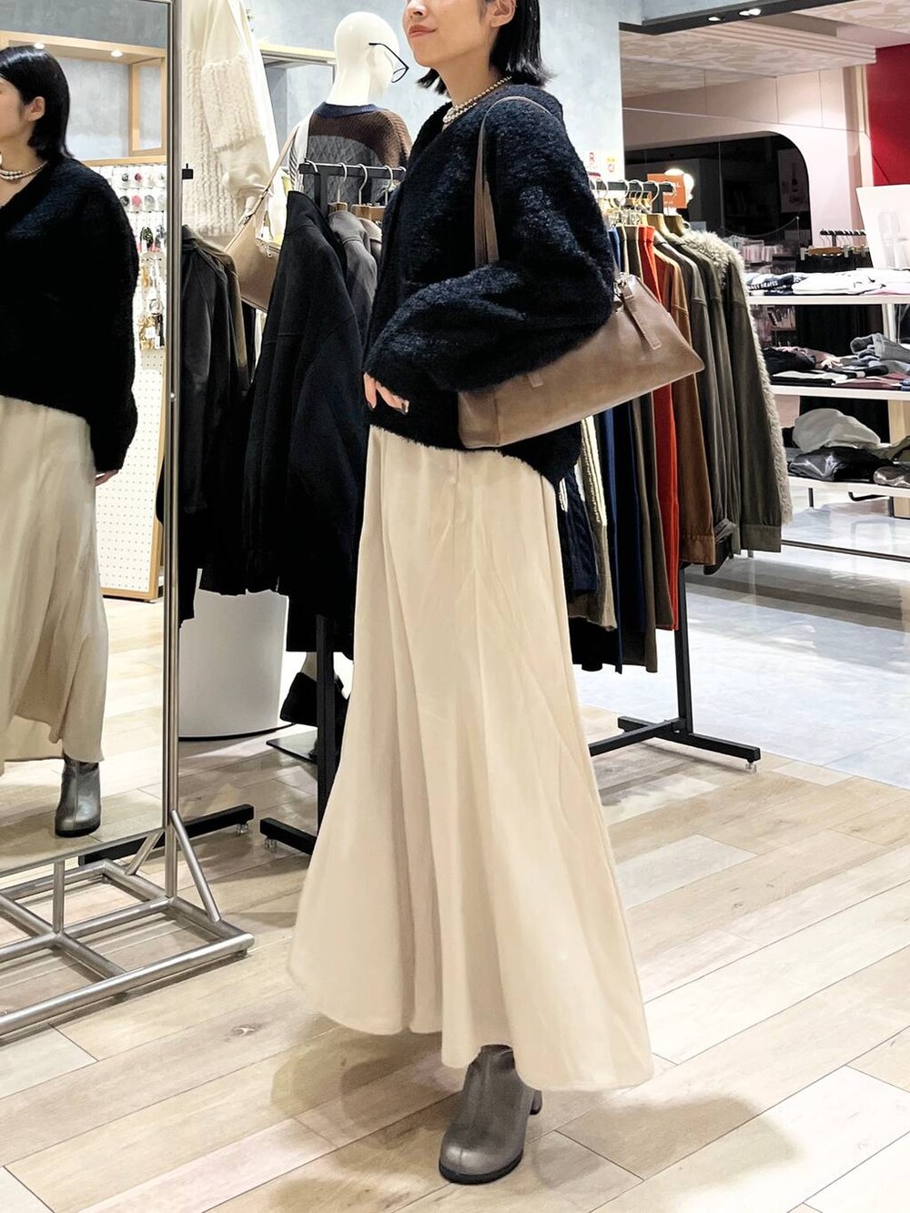 ブラウン系のボストンバッグ、ブラック系のスカート、その他のブーツを着用したレディースの秋コーディネートの3枚目の写真