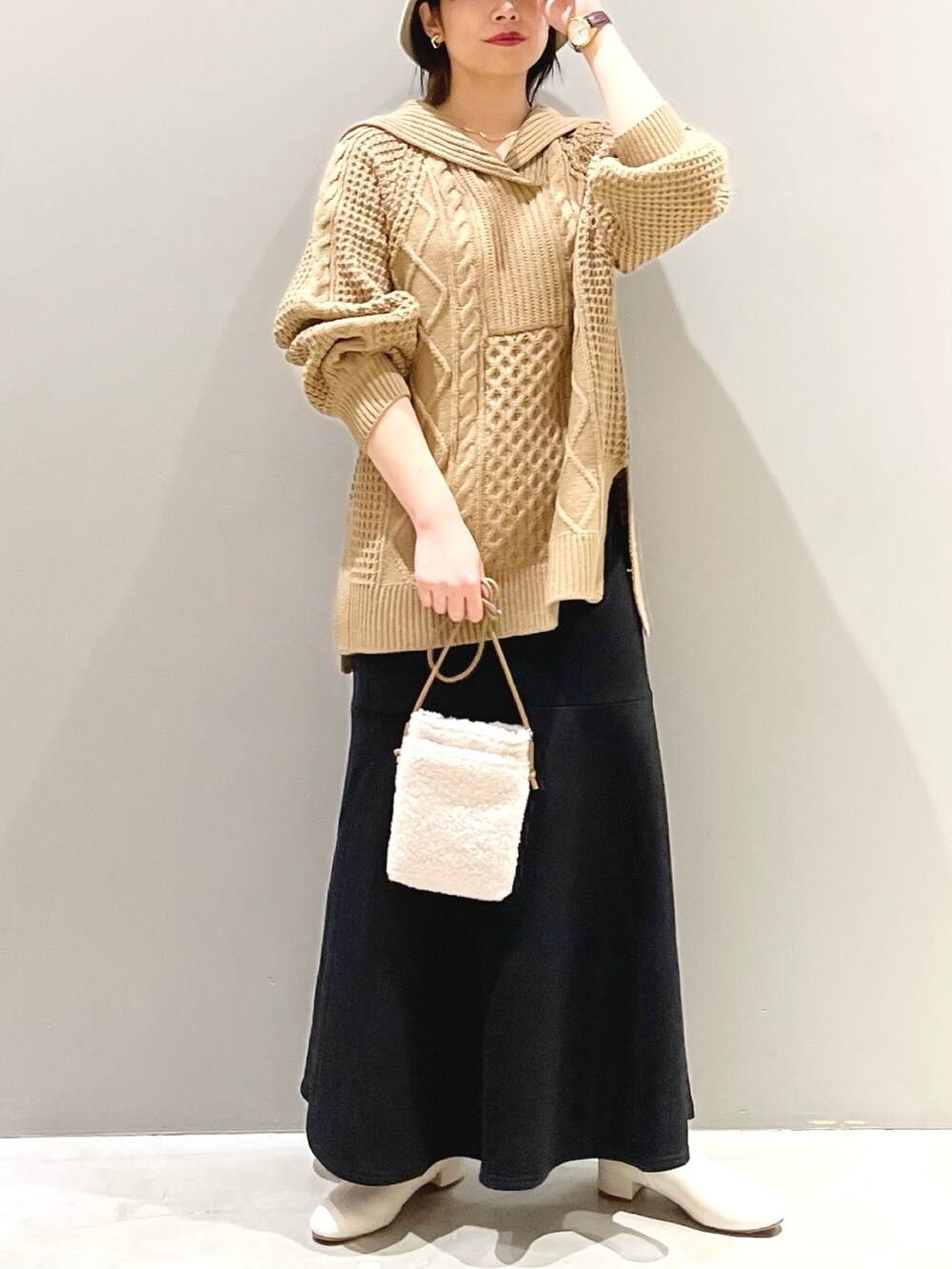 イエロー系のニット/セーター、ブラック系のスカート、ホワイト系のブーツを着用したレディースの秋コーディネートの2枚目の写真
