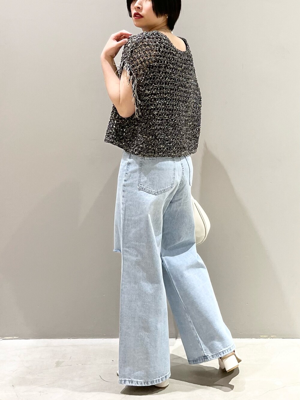 ブルー系のデニムパンツ、ホワイト系のサンダル、ホワイト系のショルダーバッグを着用したレディースの春コーディネートの4枚目の写真