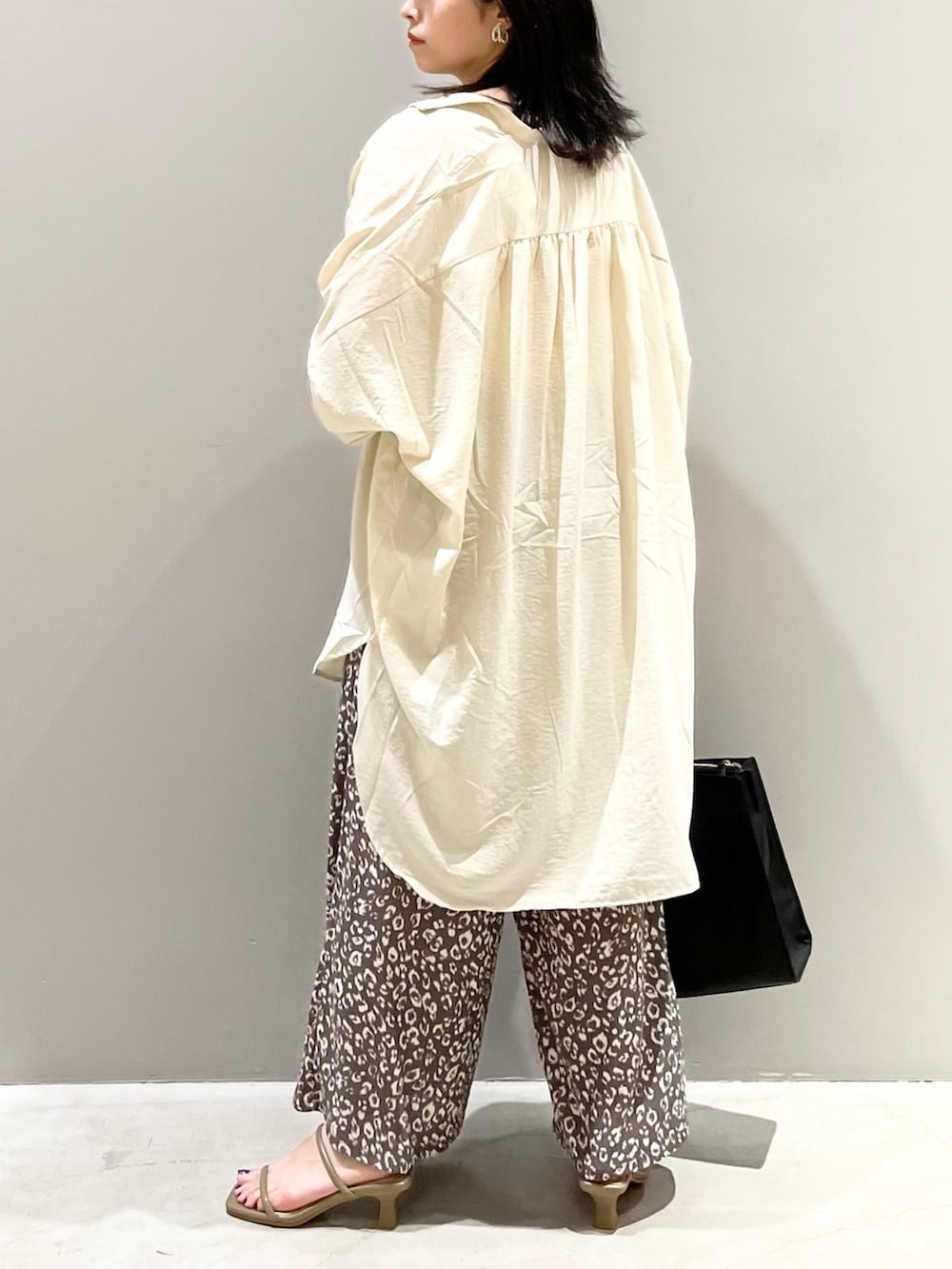 ブラック系のトートバッグ、ブラウン系のサンダル、ホワイト系のシャツ/ブラウスを着用したレディースの秋コーディネートの3枚目の写真