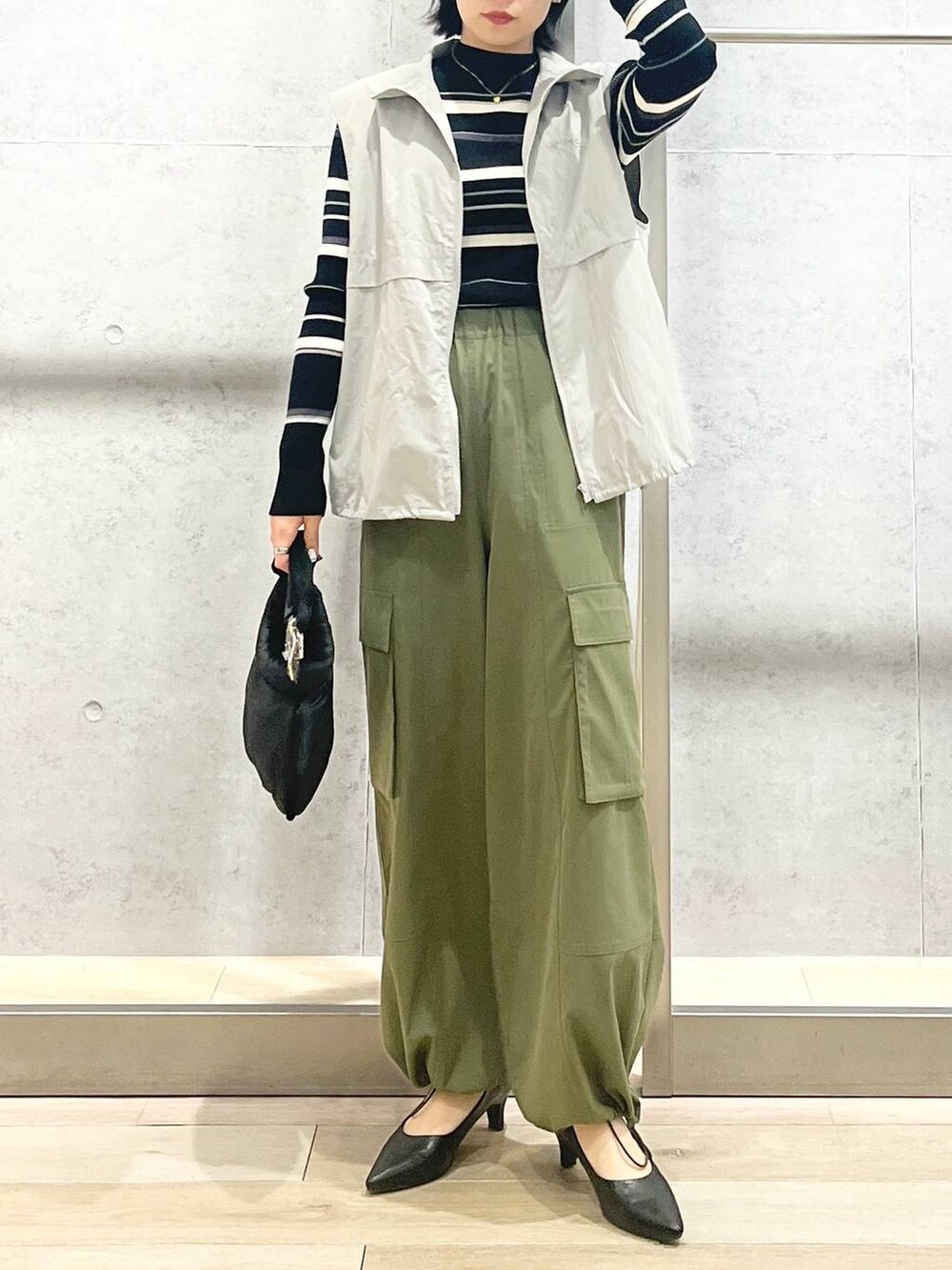 グレー系のベスト、ブラック系のハンドバッグ、グリーン系のカーゴパンツを着用したレディースの冬コーディネートの8枚目の写真