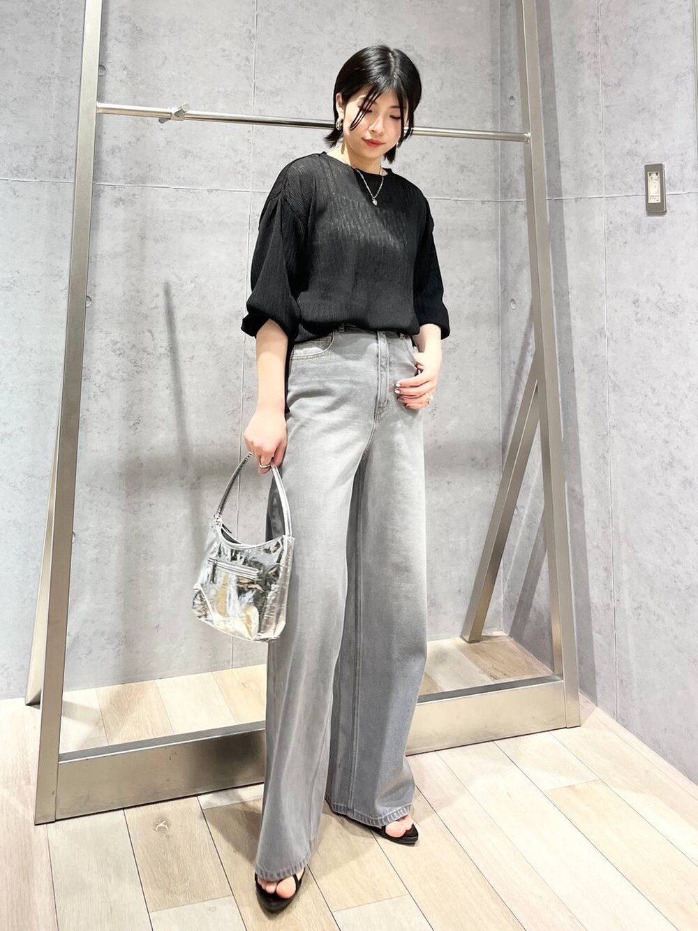 シルバー系のハンドバッグ、ブラック系のサンダル、グレー系のデニムパンツを着用したレディースの春コーディネートの8枚目の写真