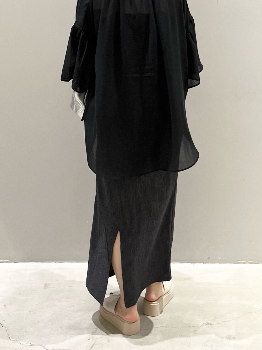 ベージュ系のサンダル、グレー系のスカート、グレー系のクラッチバッグを着用したレディースの夏コーディネートの4枚目の写真