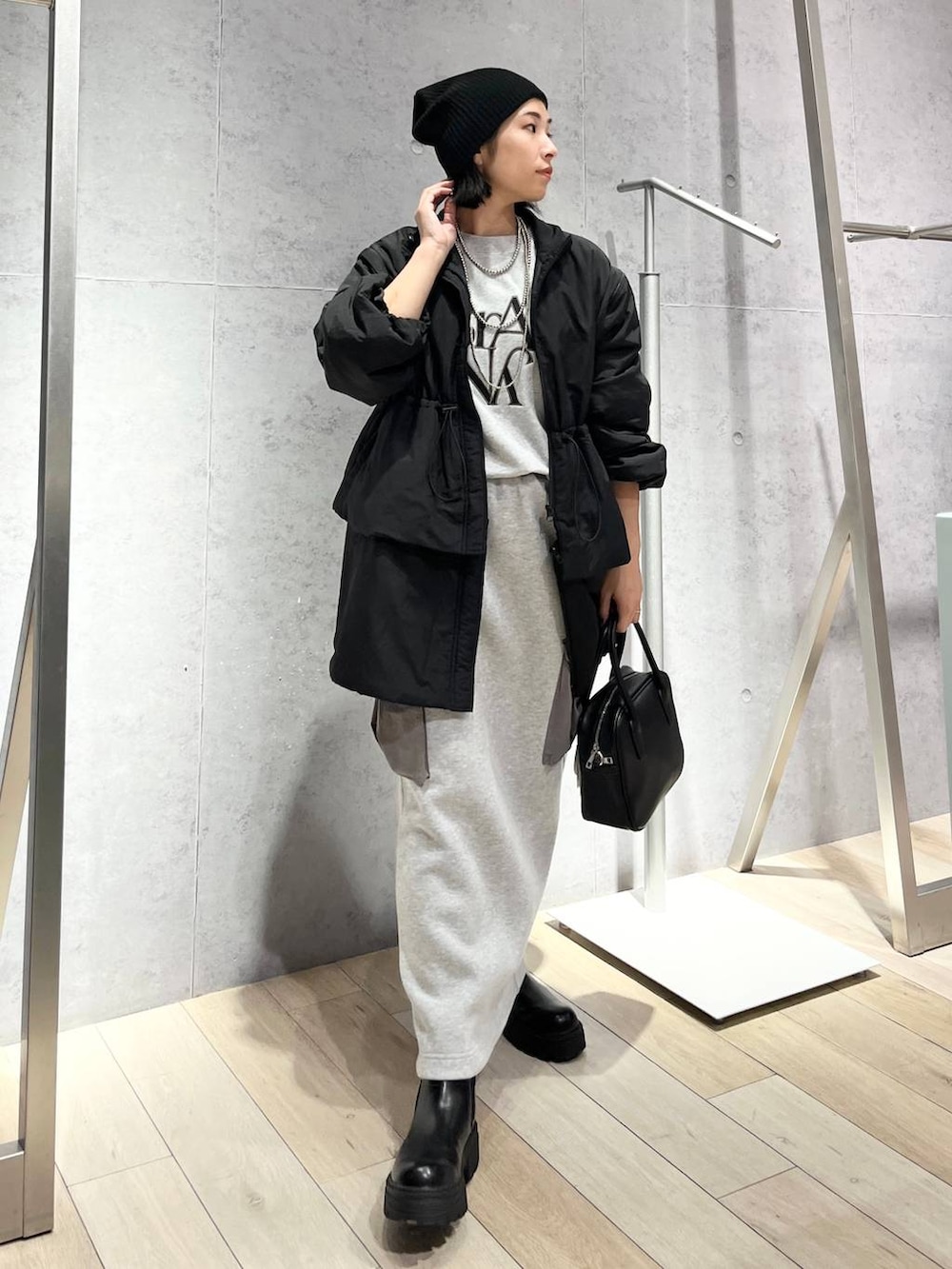 グレー系のスカート、ブラック系のボストンバッグ、ブラック系のブーツを着用したレディースの秋コーディネートの9枚目の写真